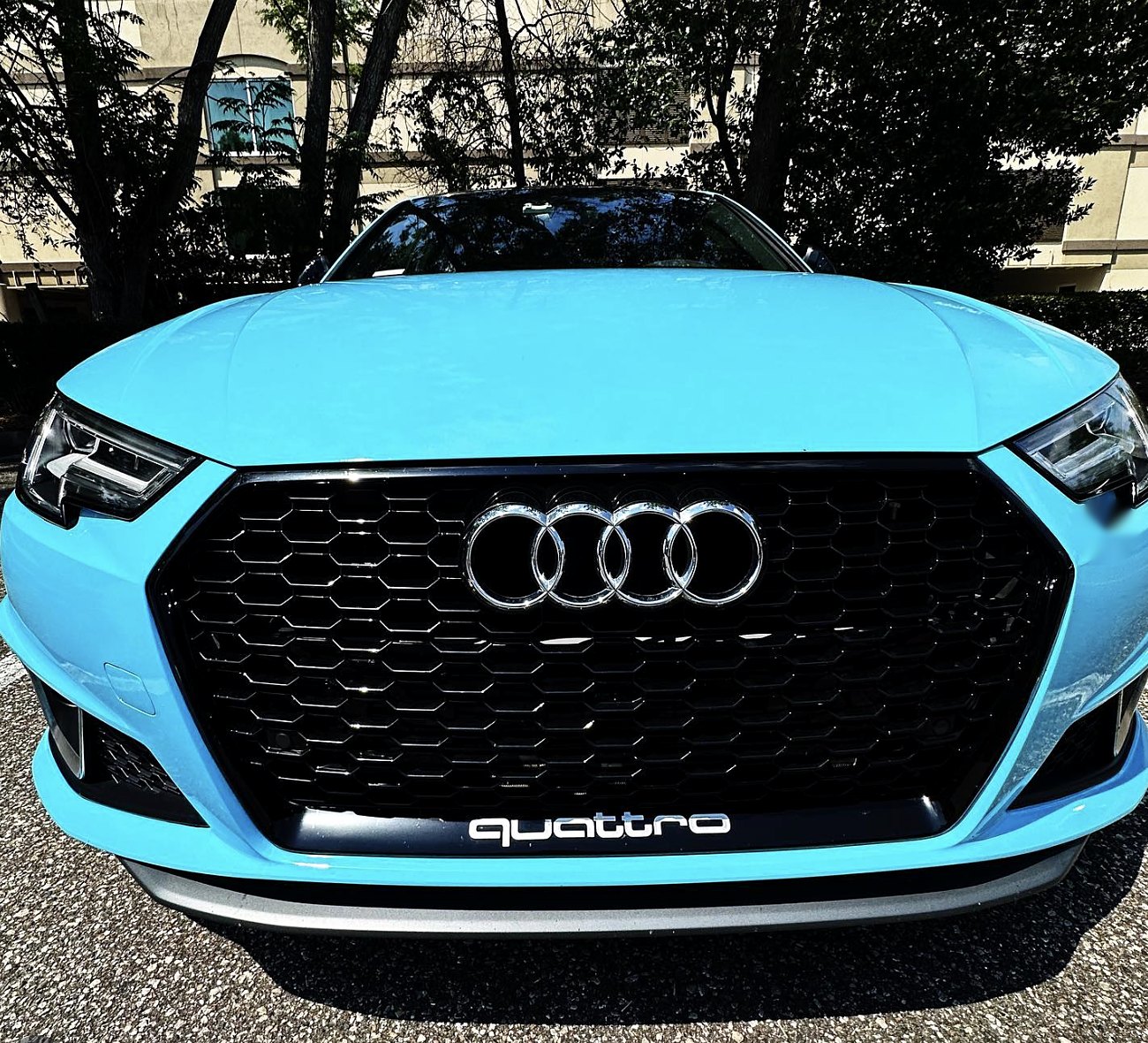 Audi A4 wrapped in gloss baby blue vinyl, front view showing the black honeycomb grille
